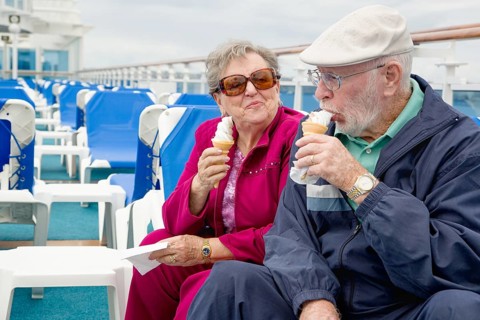 Happy senior adult couple enjoying ice cream on the deck of a luxury passenger cruise ship