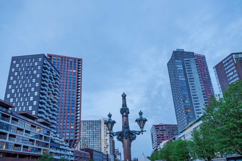 City view with modern skyscrapers, an old lamp post in the foreground and a blue sky, small harbour