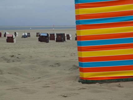 A colourful strip of sand on the beach with beach chairs in the background, extensive sand, beach