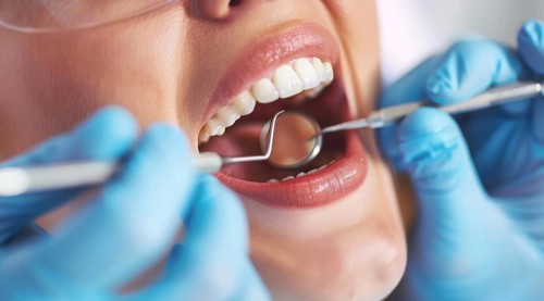 Woman with open mouth has teeth examined during checkup and fixed by a dentist in dental clinique,