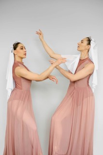 Two beautiful ballerinas practicing in front of each other over grey wall
