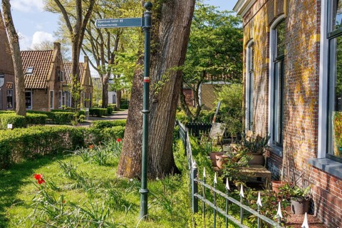 An idyllic village with manicured gardens, blooming flowers and a street sign, historic houses and