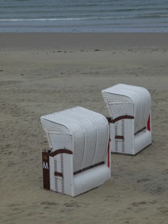 Two white beach chairs stand abandoned on a quiet beach in front of a cloudy sky, beach chairs and
