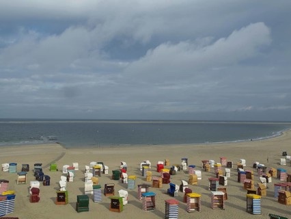 A long sandy beach with many colourful beach chairs and calm sea in the background, beach chairs