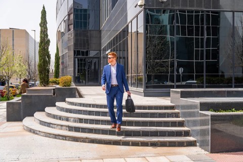Cool businessman leaving the office after work in a sunny day