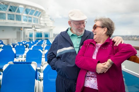 Senior adult couple enjoying the view from their passenger cruise ship railing