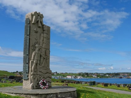 Stone memorial with flowers in a cemetery with a view of the surrounding landscape and sky, old