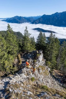 Two friends, mountaineers climbing the via ferrata to the rocky summit of the Ettaler Manndl, view