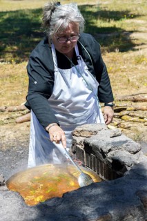 Woman cook with white apron cooking a typical Spanish paella on the fire in the countryside