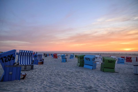 Beach chairs on the beach at sunset, focus on blue baskets, many colourful beach chairs on a warm