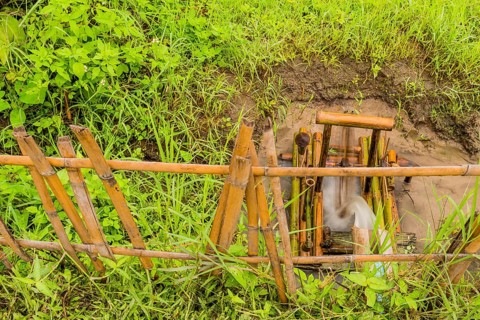 Water flowing from irrigation pipe spinning a small water wheel in canal in Chiang Khan, Thailand,