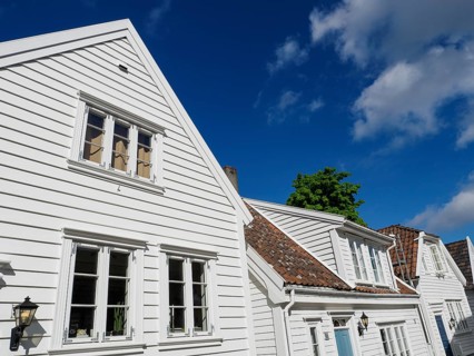 White wooden houses with red roof tiles and windows under a blue sky on a sunny day, white wooden