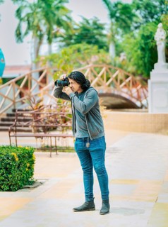 Young photographer taking photos on the street. Male photographer taking photos in a public park,