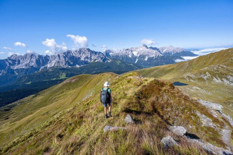 Mountaineers on a hiking trail between green mountain meadows on a mountain ridge, mountain