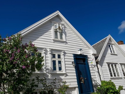 White house with blue painted door and red tiled roof under clear sky, white wooden houses with red