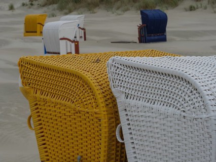 Close-up of yellow and white beach chairs on a sandy beach in cloudy weather, colourful beach