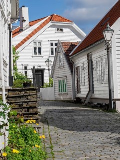 Cosy street with white wooden houses, flowers and a street lamp in sunny weather, white wooden