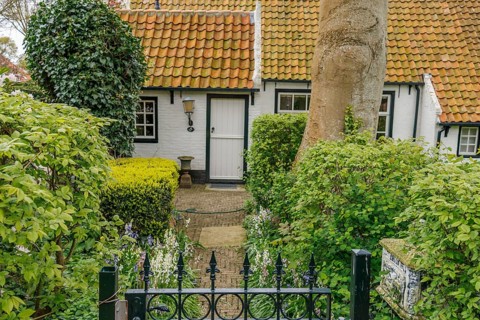 Charming house with garden and red tiled roof, surrounded by bushes, old houses with green gardens