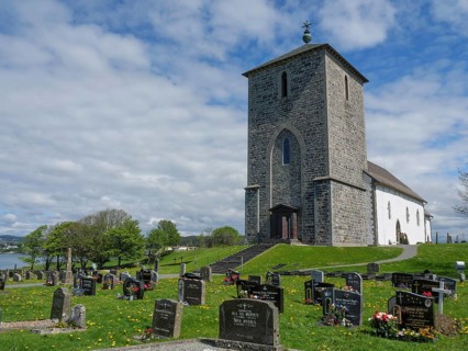 Old church on a cemetery under a blue cloudy sky, old stone church and many gravestones on the