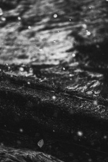 Artistic detail shot of water with water droplets in the foreground. Taken in black and white at a