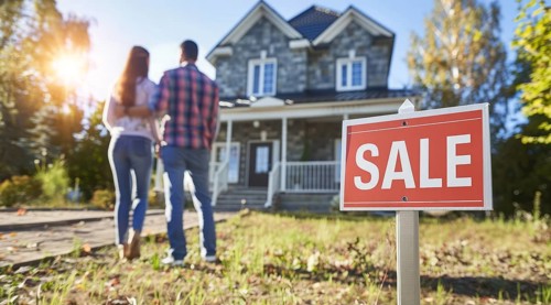 House for sale. Happy new buyer couple stand in front of modern luxury real estate intending to