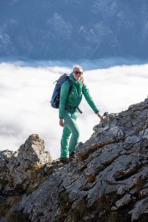 Hiker at Ettaler Manndl, view over mountain landscape and sea of clouds, high fog in the valley,