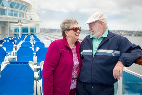 Senior adult couple enjoying the view from their passenger cruise ship railing
