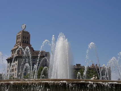 A fountain with powerful water jets in front of a historic building under a blue sky, fountain with