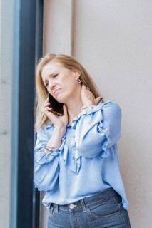Tired woman talking on the phone with neck pain