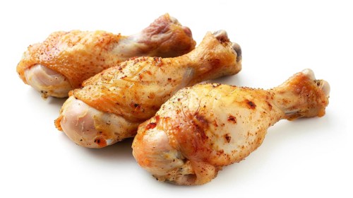 Three seasoned roasted chicken drumsticks on white, AI generated