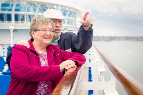 Senior adult couple enjoying the view from their passenger cruise ship railing