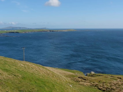 View of a wide green plain sloping down to the deep blue sea, green meadows by a deep blue sea and
