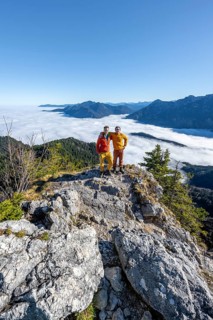 Two friends put their arms around each other's shoulders, mountaineers on the rocky summit of the