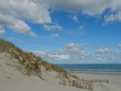 View of the beach with sand dunes and the sea under a blue cloudy sky, dunes on an island with a