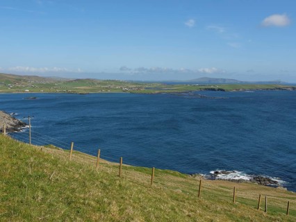 View of grassy plains and deep blue sea under a clear sky, green meadows by a deep blue sea and a