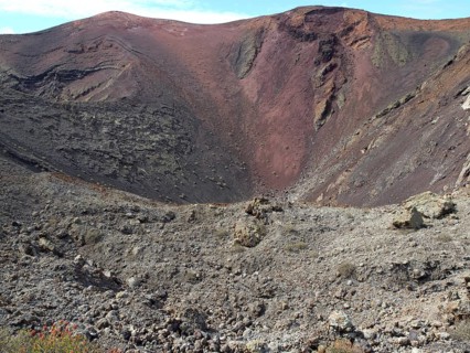 A broad volcano with a crater and red earth tones in a barren landscape, barren landscape with