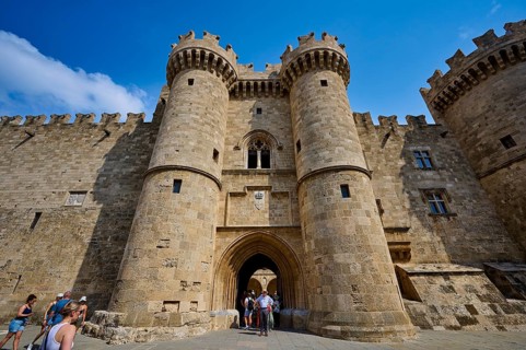 Super wide angle shot, group of visitors approaching the entrance of a large castle with two round