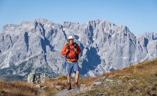 Mountaineer on hiking trail in front of rocky mountain peaks, behind Sesto Dolomites, Carnic Main