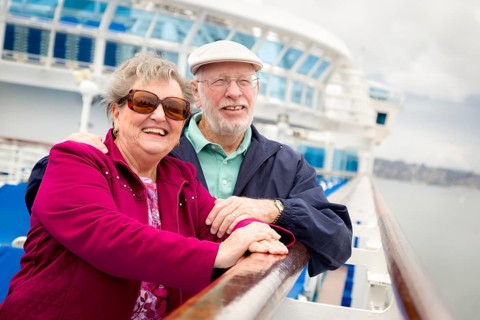 Senior adult couple enjoying the view from their passenger cruise ship railing