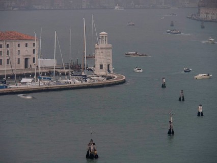 Venice harbour with numerous boats and yachts and a harbour wall in a foggy atmosphere, church