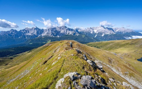 Mountaineers on a hiking trail between green mountain meadows on a mountain ridge, mountain