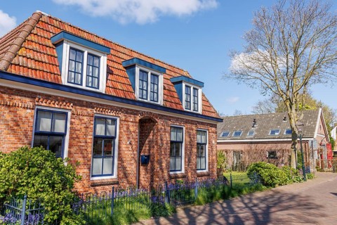 A large brick house with red tiled roofs and white window frames in a quiet street, historic houses