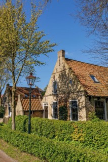 Cosy brick houses with red roofs, lampposts, green hedges and lush trees, historic houses in a