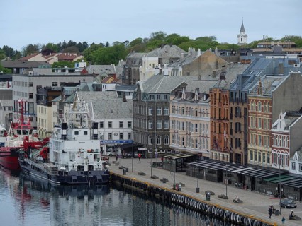 Waterfront of a town with many old and new buildings, yachts and fishing boats moored at the quay,
