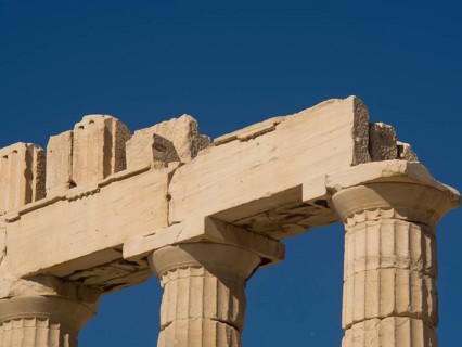 Close-up of ancient marble columns of a ruin in front of a clear blue sky, historical columns and