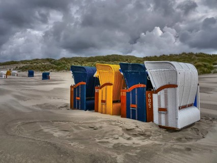A group of colourful beach chairs on the coast in unstable weather, colourful beach chairs on the