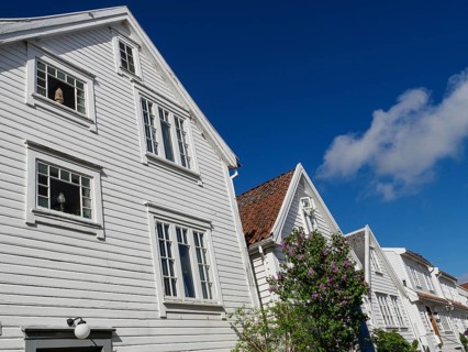 White wooden house with red tiled roof under sunny blue sky, historical architecture, shutters and