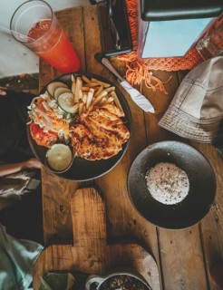 Top view of traditional roast chicken with french fries and salad served on wooden table