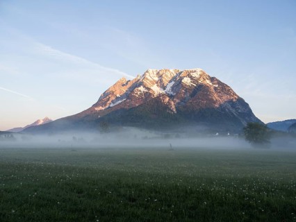 Morning light falls on a mountain peak, Grimming, early morning fog on the meadow, near Irdning,