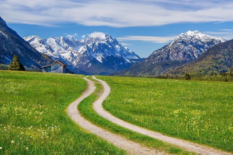 Mountain path through spring meadow with hay barn in front of Zugspitzgruppe 2962m in the